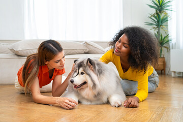 Two women are laying on  floor next to  large dog