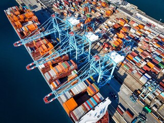 Vado Gateway, Italy - 21 September 2025: Aerial view of the bustling port, where vibrant container stacks meet the deep blue sea under the watchful gaze of towering cranes.