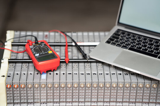 Laptop and multimeter testing electric car hybrid battery pack