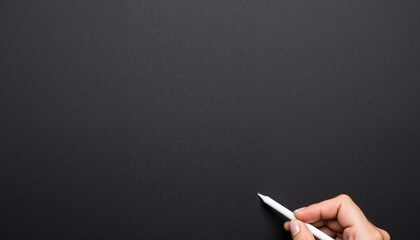 Hand holding white pen writing on black chalkboard surface  