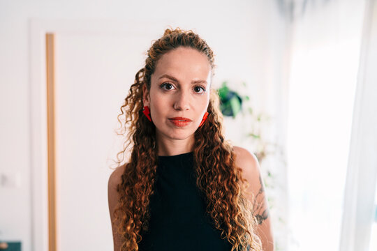 Portrait of woman with curly hair and serious expression indoors