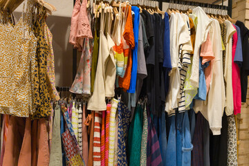 colorful clothes on hangers multiple items of clothing hanging on shop rack showcasing diverse styles and colors in store display