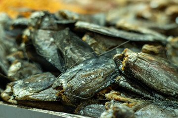 Close-up of dried fish stacked for sale at a traditional market, showcasing preserved seafood as a local food product and culinary ingredient