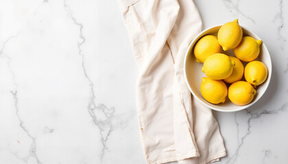 Fresh lemons in white bowl on marble countertop with linen napkin