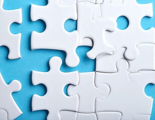 Fototapeta premium Close-up of several white jigsaw puzzle pieces on a light-blue background, some connected, some separate, showing a gap