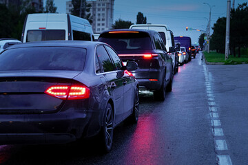 Traffic congestion during evening rush hour on a wet road in the city with vehicle lights reflecting on the pavement
