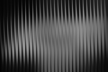 Abstract dark background with vertical ribbed texture and light reflections