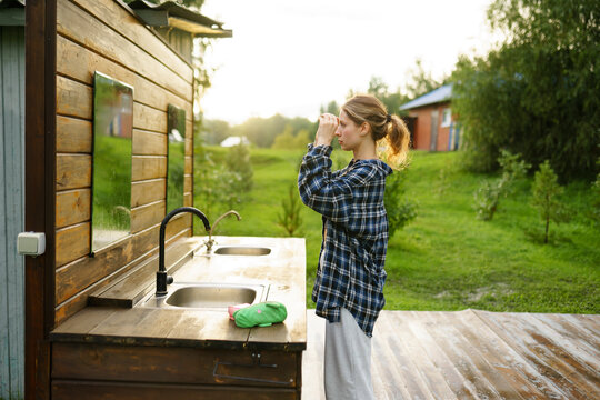 Woman putting on make-up at outdoor washbasin in summer morning
