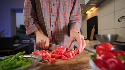 Close up of male hands slicing fresh tomatoes for salad on wooden board in authentic kitchen evening lifestyle atmosphere healthy eating scene.
