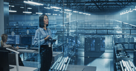Beautiful Asian Female Cybersecurity Expert Works on Her Laptop Computer in a Modern Facility, Running Diagnostic Tests to Identify Network Vulnerabilities in a Data Center with Server Racks