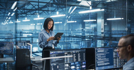 Asian Female DevOps Engineer Monitoring Automation Scripts on Her Tablet Computer, Streamlining Processes of the Data Center IT Infrastructure. Software Specialist Working in Data Protection Field