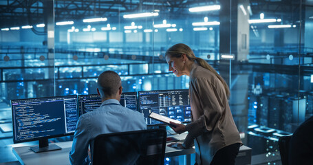Male Engineer and Female Team Leader Collaborate on a Project in a Modern Data Center Office. Specialists Analyzing Complex Systems on Multiple Screens to Improve Software  Performance