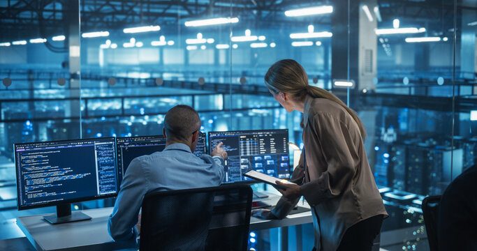Male Engineer and Female Team Leader Collaborate on a Project in a Modern Data Center Office. Specialists Analyzing Complex Systems on Multiple Screens to Improve Software  Performance