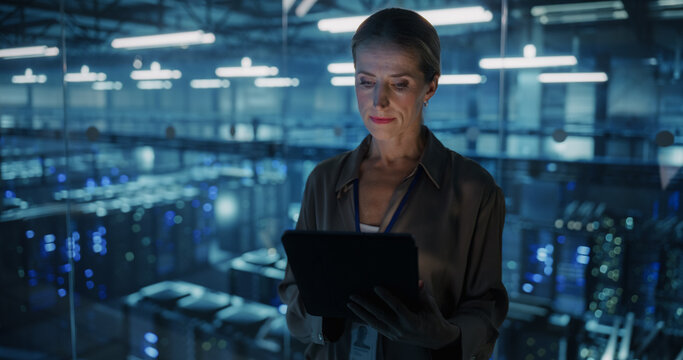Portrait of a Female Systems Administrator Standing in a Glass Office, Adjusting Configuration Settings on Her Tablet Computer, Operating Cloud Services Servers for Artificial Intelligence Training