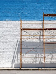Fototapeta premium Scaffolding Against a Freshly Painted Blue and White Wall in a Construction Zone