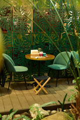 A Cozy Green Indoor Seating Area Featuring Plants and a Table for Relaxation and Comfort