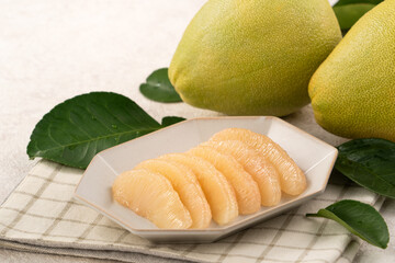 Fresh pomelo fruit with leaf on white table background.