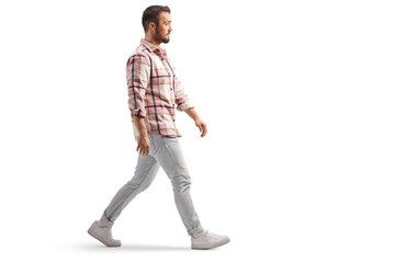 Naklejka premium Full length profile shot of a man in jeans and checkerd shirt walking