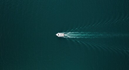 Aerial view of a white boat leaving a wake on the deep blue ocean