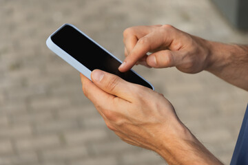 Man using and texting mobile phone. Check apps, focused on device, chatting or browsing internet. Online. Outdoors.