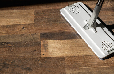 Top view of a flat microfiber mop on a wooden floor in natural light