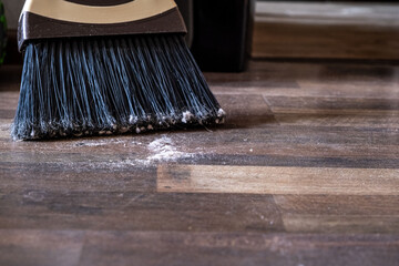 Close-up of a broom sweeping dust and dirt on a wooden floor