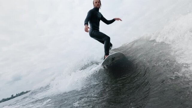 Surfer gliding on ocean wave, showcasing balance and skill in dynamic water scene