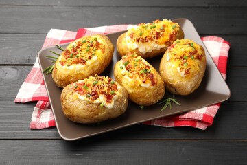 Tasty stuffed baked potatoes on black wooden table