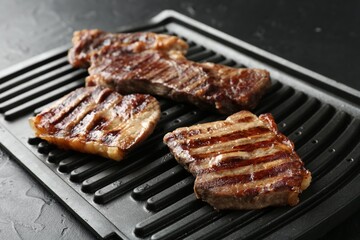 Delicious grilled beef meat on black textured table, closeup