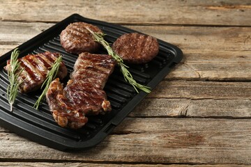 Delicious grilled beef meat with rosemary on wooden table, closeup. Space for text