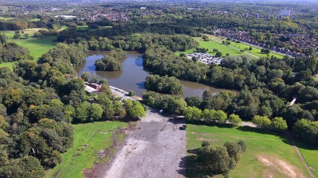Aerial video of Heaton Park boating lake, open fields, and woodland on a sunny day in Manchester.