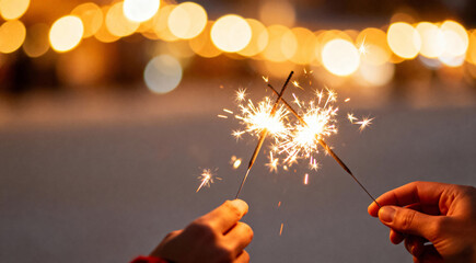 Hands Holding Burning Sparklers for a Festive Holiday Celebration at Night