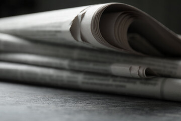 Stack of newspapers on grey table, closeup