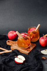 Warm apple cider with cinnamon sticks and star anise in glasses on dark