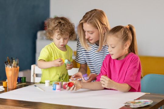 Happy family painting together. Young mother learn her little children to draw. Family art therapy and having fun time at home.