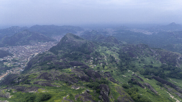 Aerial view of a dramatic landscape where rocky outcrops meet lush green vegetation under a vast sky, Idanre Hills, Ida really, Ondo, Nigeria.