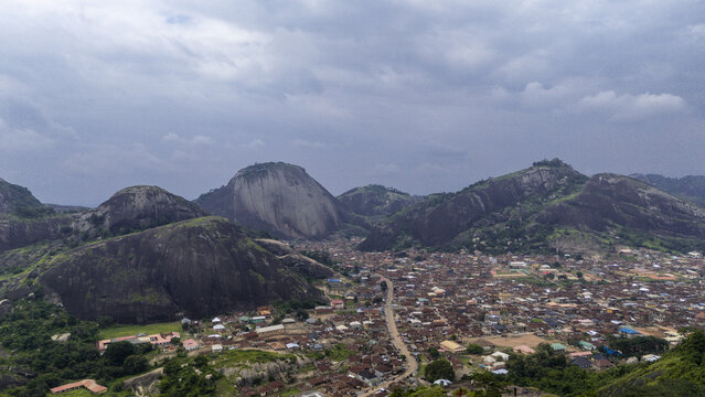 Aerial view of ancient hills rise majestically over a sprawling town under a cloudy sky, Idanre Hills, Ida really, Ondo, Nigeria.