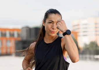 Young female doing warming up outdoors. Sweating young woman practicing shadow boxing.