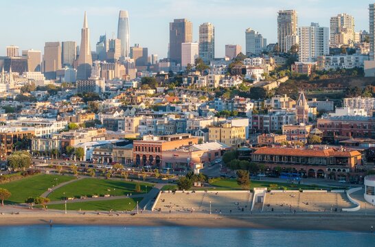 Aerial view of Ghiradelli Square, behind which skyscrapers, buildings, and parks, are all bathed in the warm glow of the sun, San Francisco, California, United States.