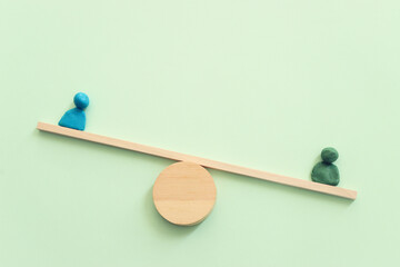 Concept image of figures on wooden scale. Idea of measurement and finding balance