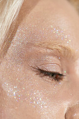 Fototapeta premium Blonde beauty shines bright with glitter in studio portrait session