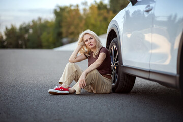 Woman sitting next to car for remote travel adventure