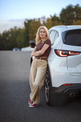 A beautiful woman stands next to her car