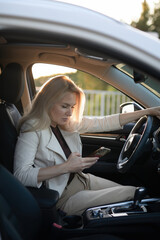 Woman sitting in car and using her smartphone.