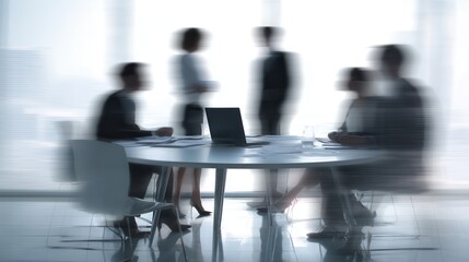 A blurred meeting scene with silhouettes of people discussing around a table in a modern office setting.