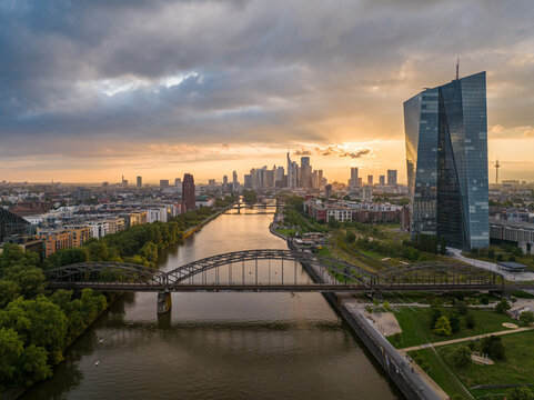 Aerial view of the Main river reflecting the skyline, spanned by bridges near the European Central Bank under a dramatic sky, Frankfurt am Main, Hessen, Germany.