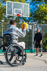 Obraz premium Man in wheelchair playing basketball with friend
