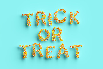 Trick or treat is written isolated on blue background. The letters are made out of candy corn. 3d illustration