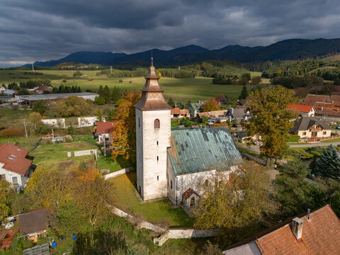 Aerial view of the ancient church with its weathered stone and copper-green roof nestled amidst a tapestry of autumnal trees, H&Atilde;&iexcl;j, &Aring;&frac12;ilina Region, Slovakia.