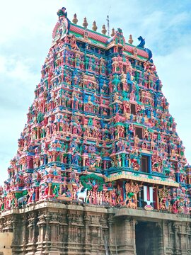 Majestic gopuram of the famous Alagar temple in Madurai, Tamilnadu, adorned with vibrant sculptures and intricate Dravidian carvings, standing tall against a bright blue sky, reflecting rich culture